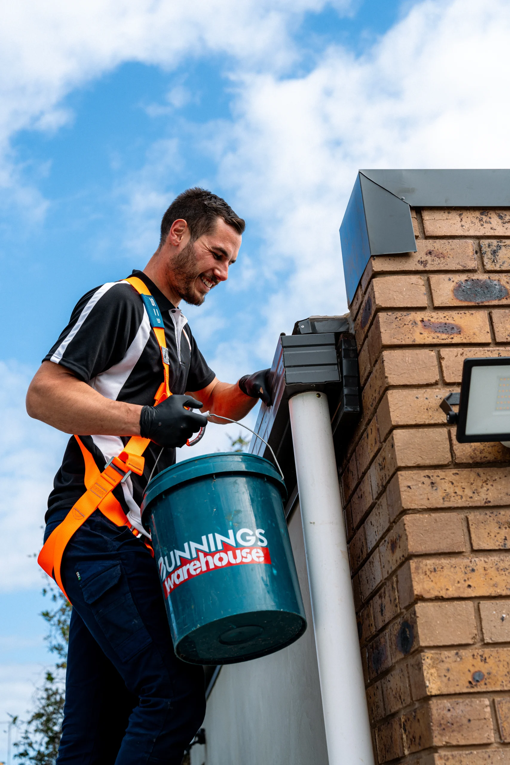 Roof plumber clearing gutters on Melbourne home, box gutter and downpipe maintenance